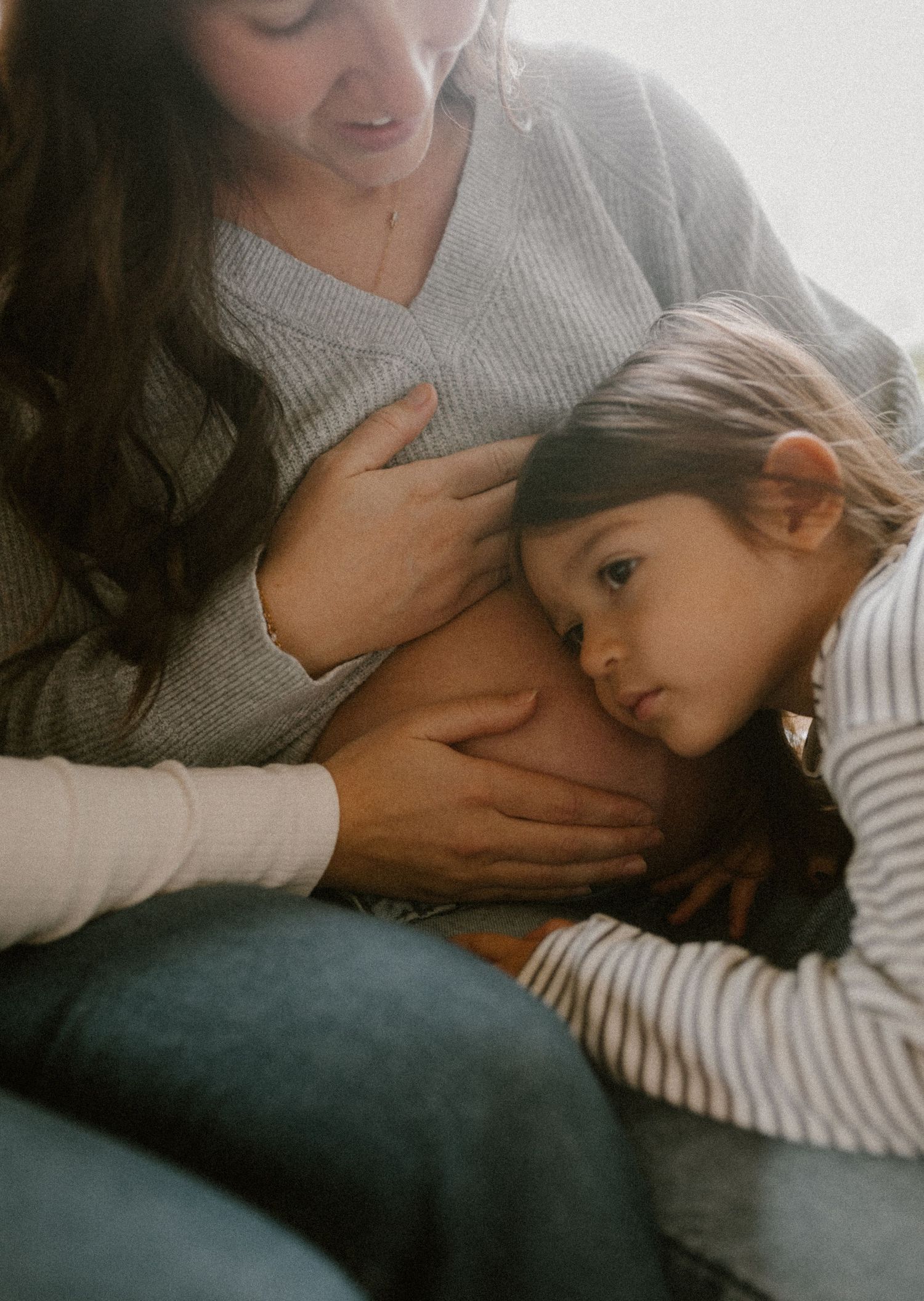 Tender moment of embracing and cuddling mom's belly in soft sweaters.