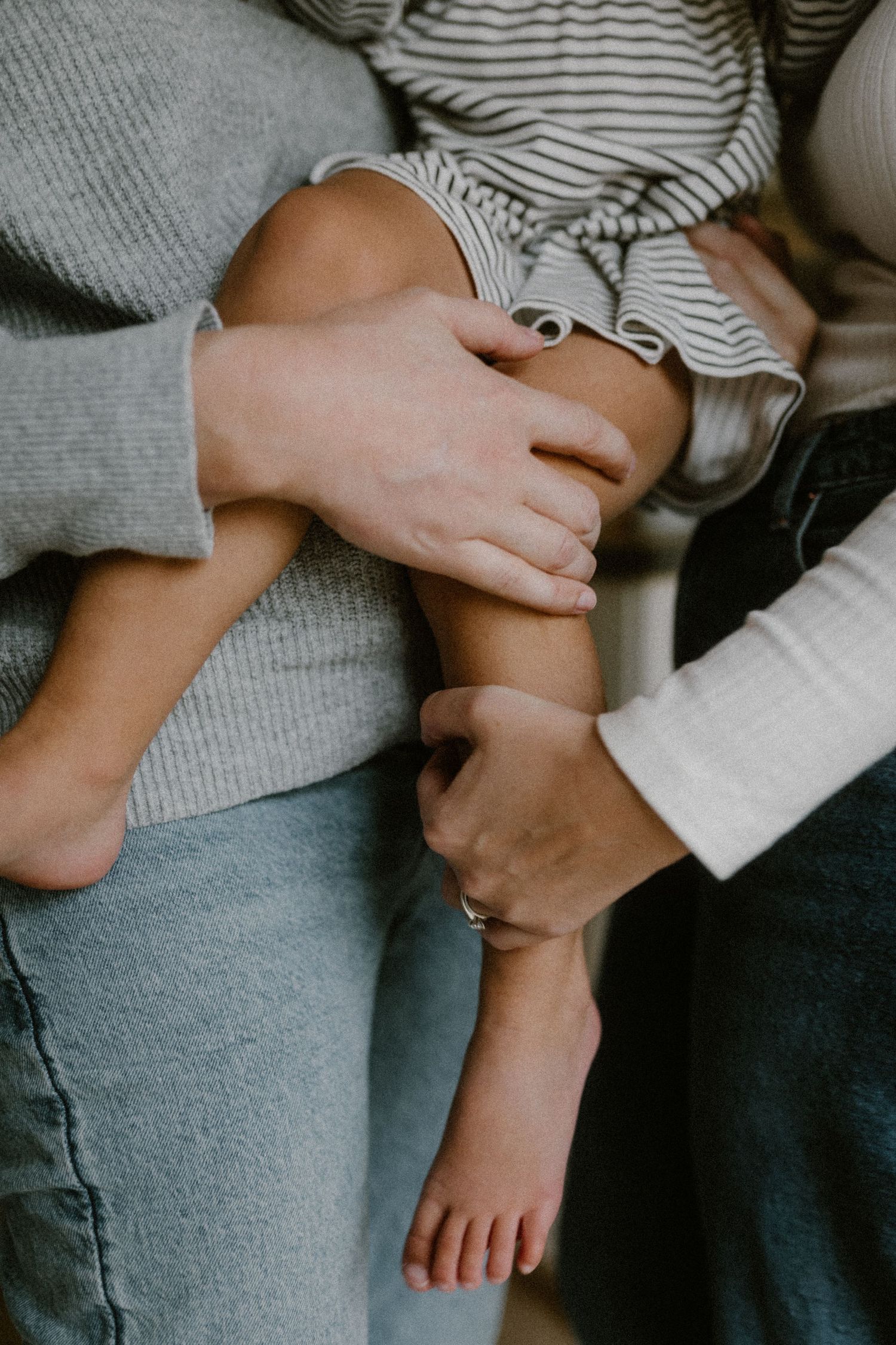 Close-up of hands tenderly touching in casual intimate moment wearing grey and white clothing.