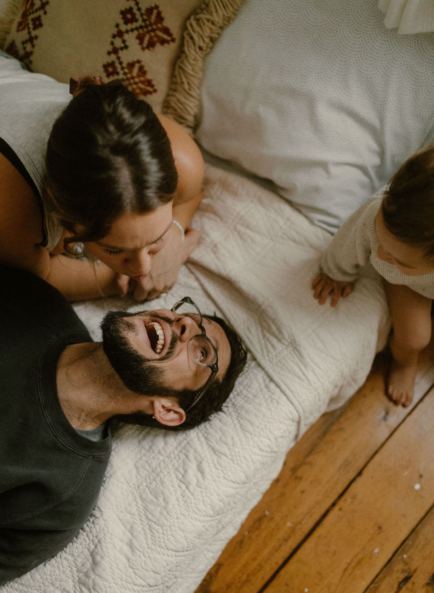 Candid moment of joy and laughter shared between family members on white bedding.