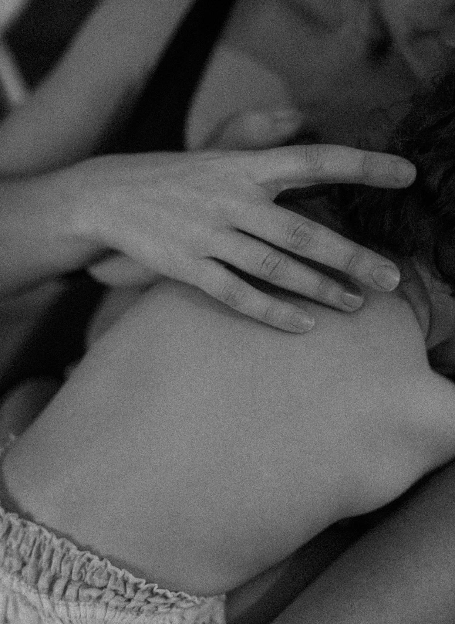Close-up black and white image of gentle hand touch on child's hair.
