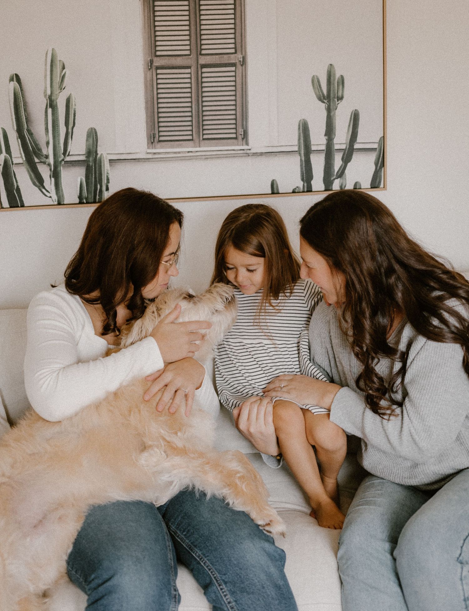 Cozy indoor gathering with fluffy dog and cactus wall art.