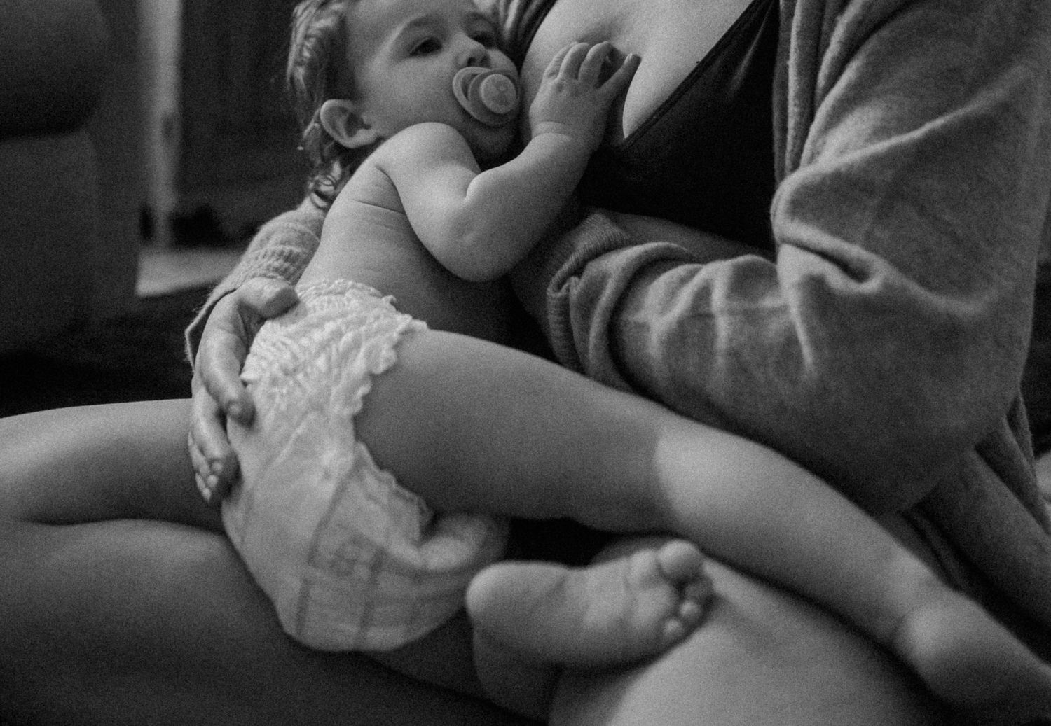 Black and white intimate portrait of nurturing moment between parent and infant.