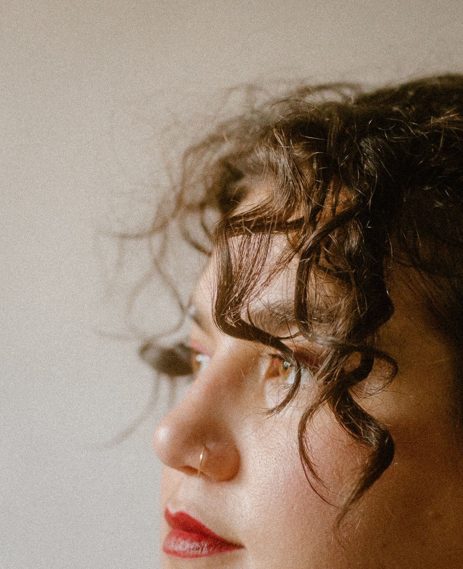 Side profile capturing elegant features and curly hair in warm tones.