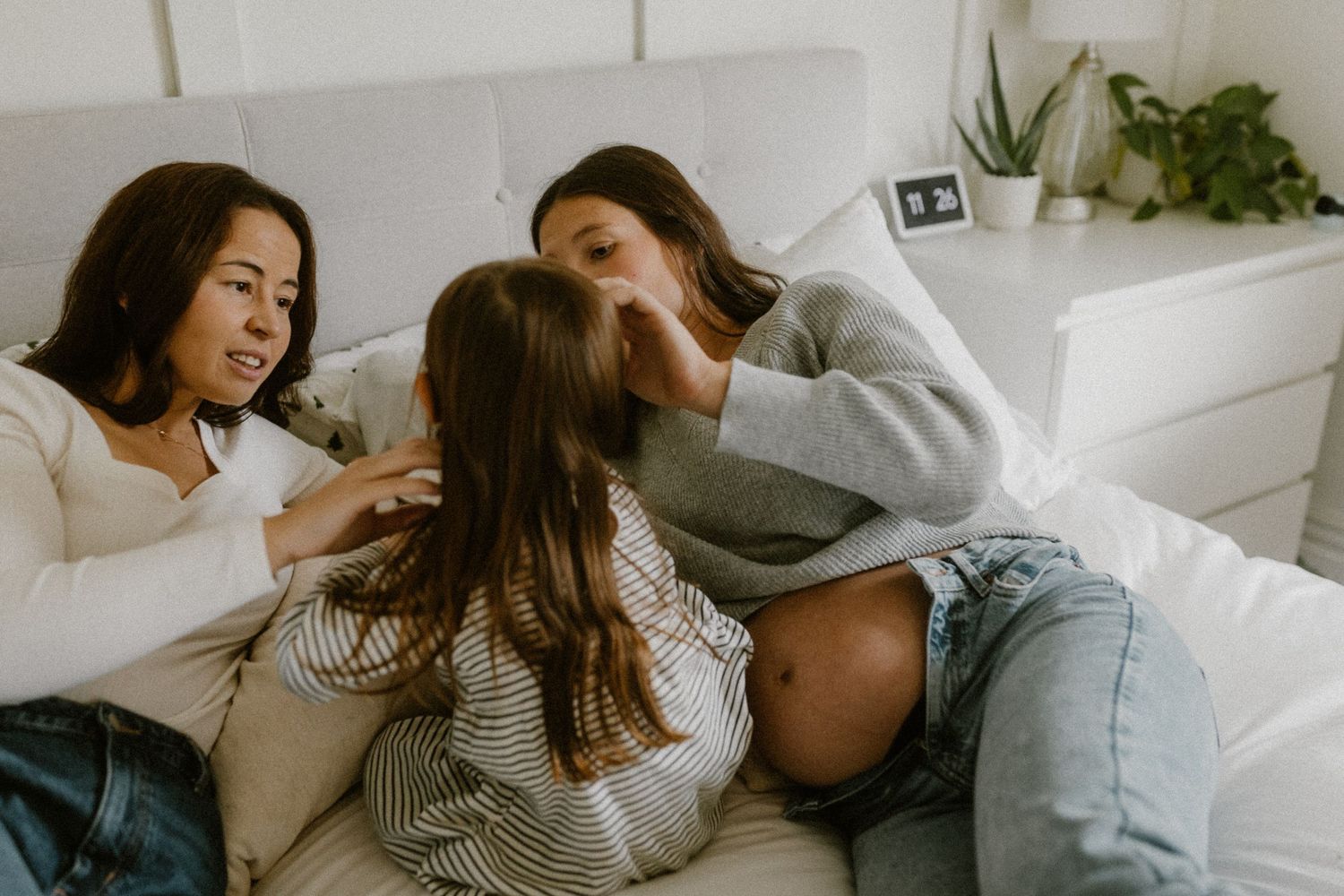 Three people share an intimate moment of laughter and connection on a couch.