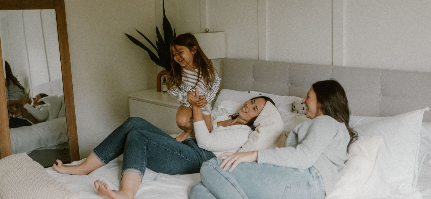 Playful moment captured on a comfortable bed in a sunlit room.