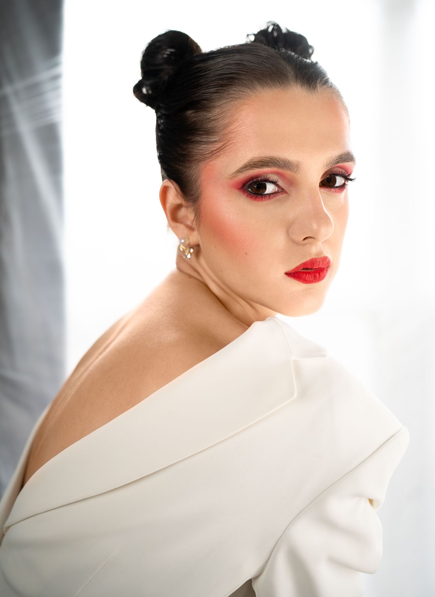 Studio portrait of model in white blazer with red lipstick and elegant updo.