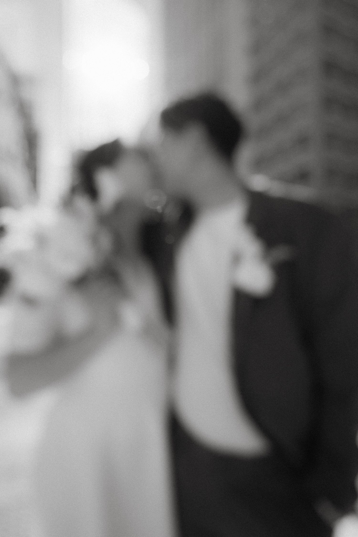 A soft, dreamy black and white wedding photo with a romantic blurred effect shows a loving couple in an intimate moment.