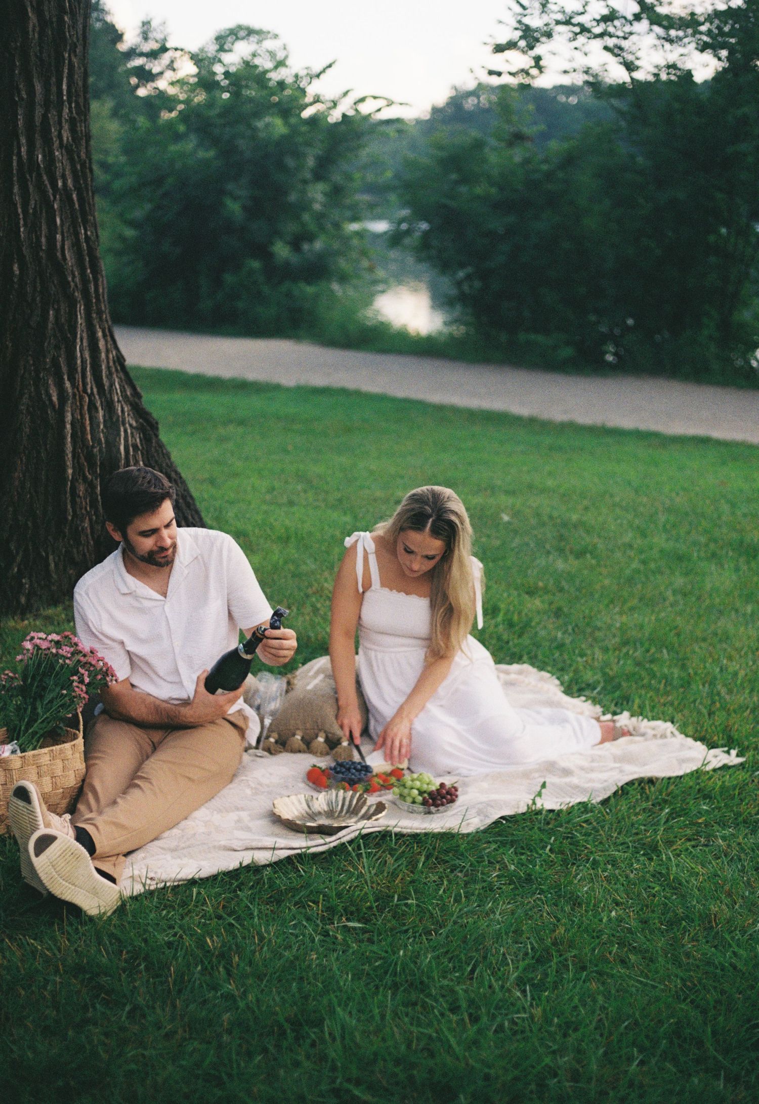 A couple enjoying a romantic picnic on a blanket in a grassy park setting during a summer afternoon.