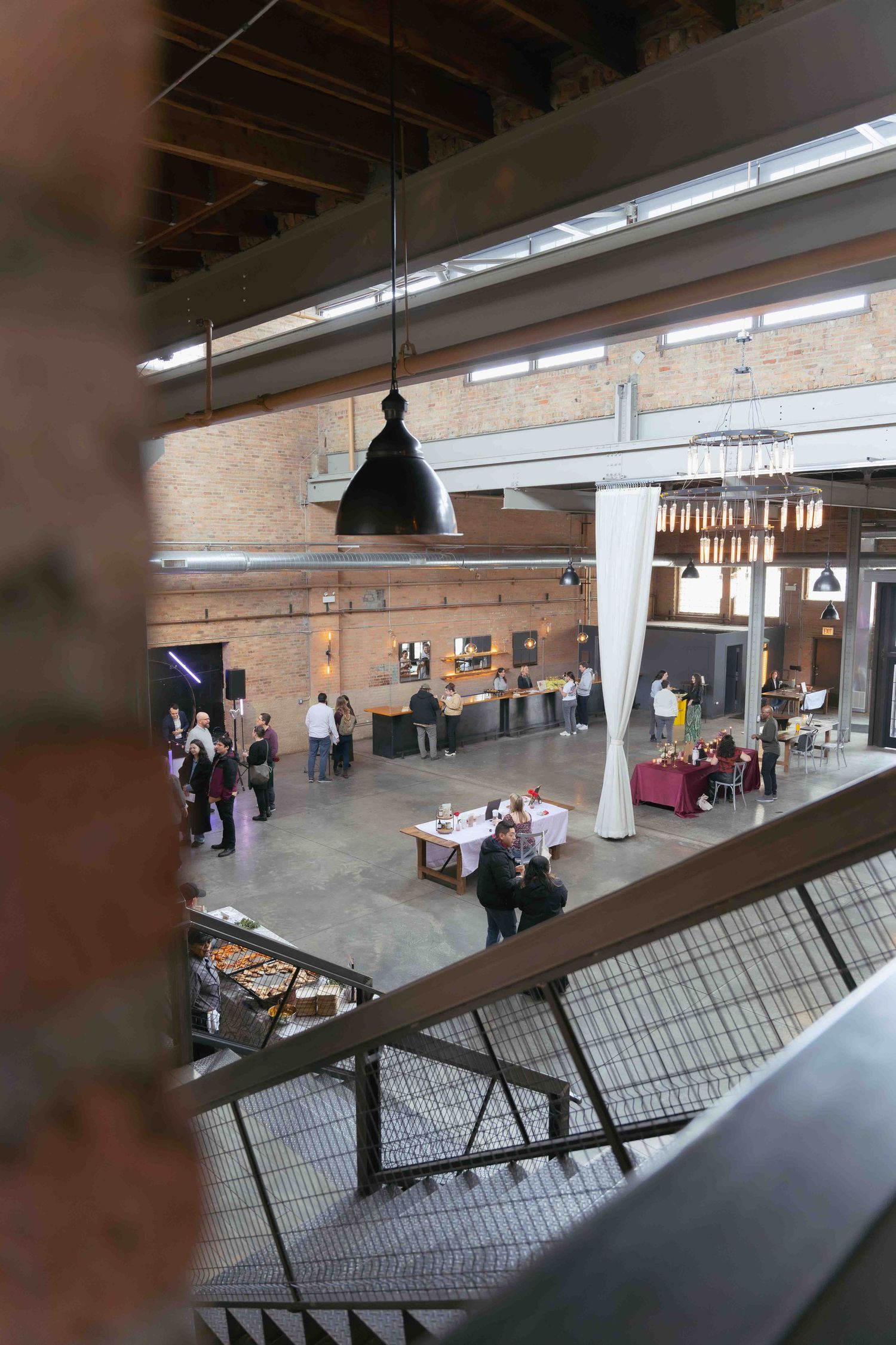 Industrial event venue with exposed ceiling and pendant lighting viewed from above mezzanine level. At Fairlie, Chicago