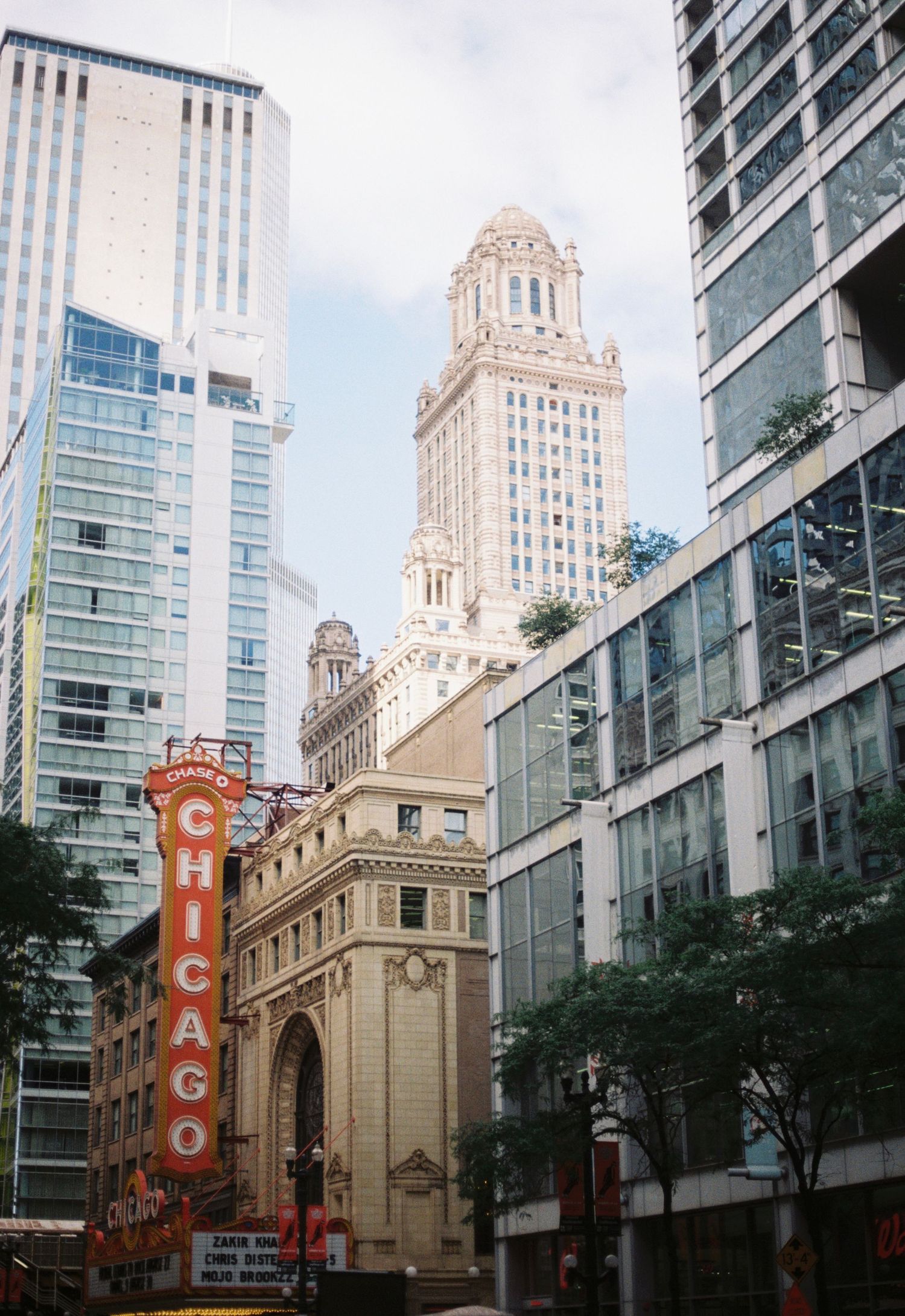 Historic Chicago Theatre building with glass skyscrapers and ornate architecture along State Street in downtown Chicago.