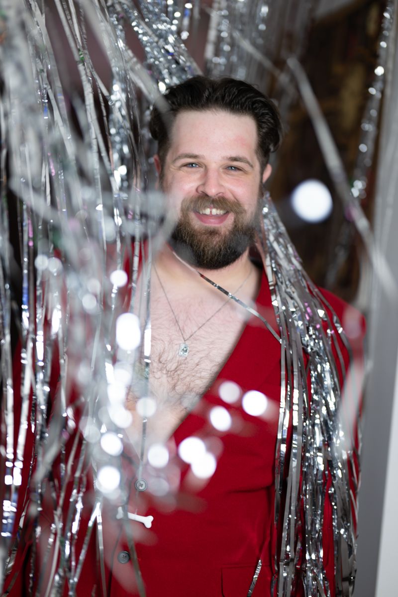 Three similar photos show someone in a red shirt smiling through shimmering silver tinsel decorations.