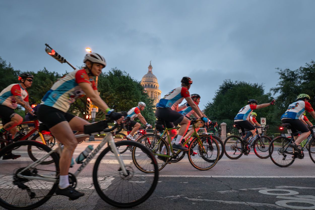 Cyclists race past the Texas State Capitol building at dusk in Austin, TX.