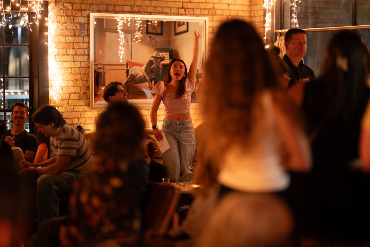 People dancing and socializing in a dimly lit brick-walled venue with warm ambient lighting.