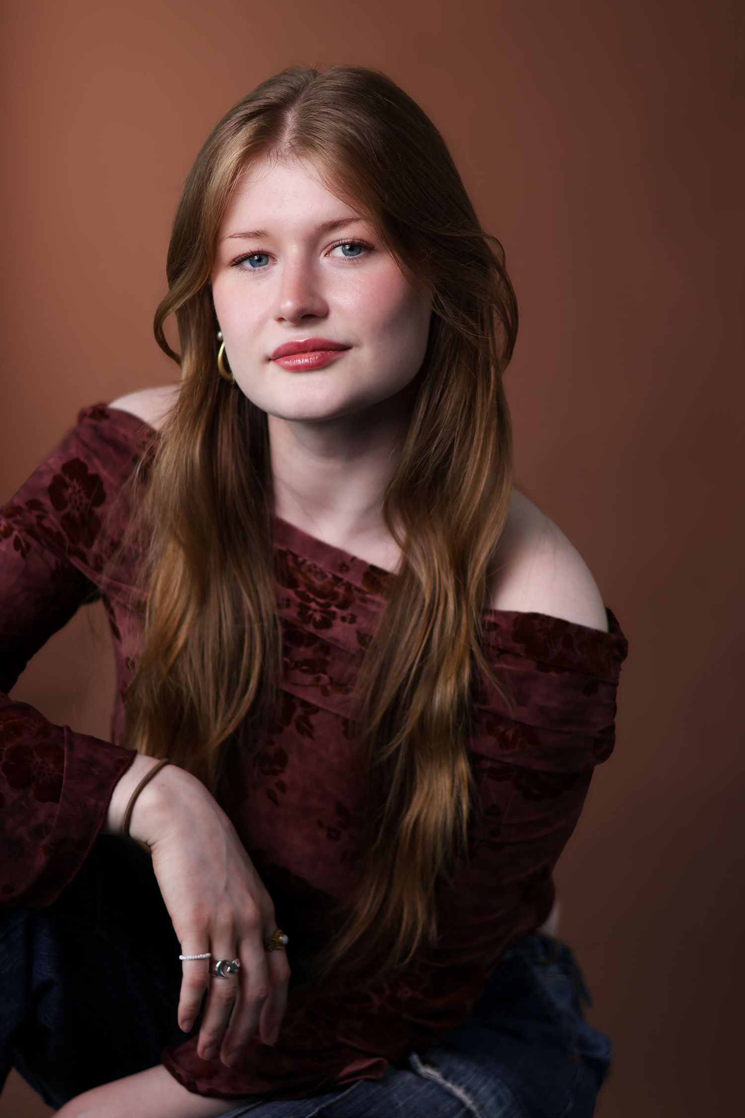 A portrait series in warm brown tones showing someone in a burgundy ruffled top with flowing auburn hair.