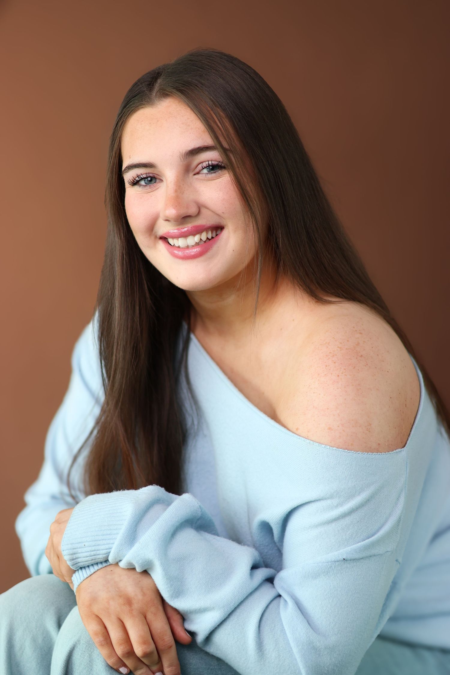 A series of photos showing someone in a cozy light blue sweater posing against a brown background.