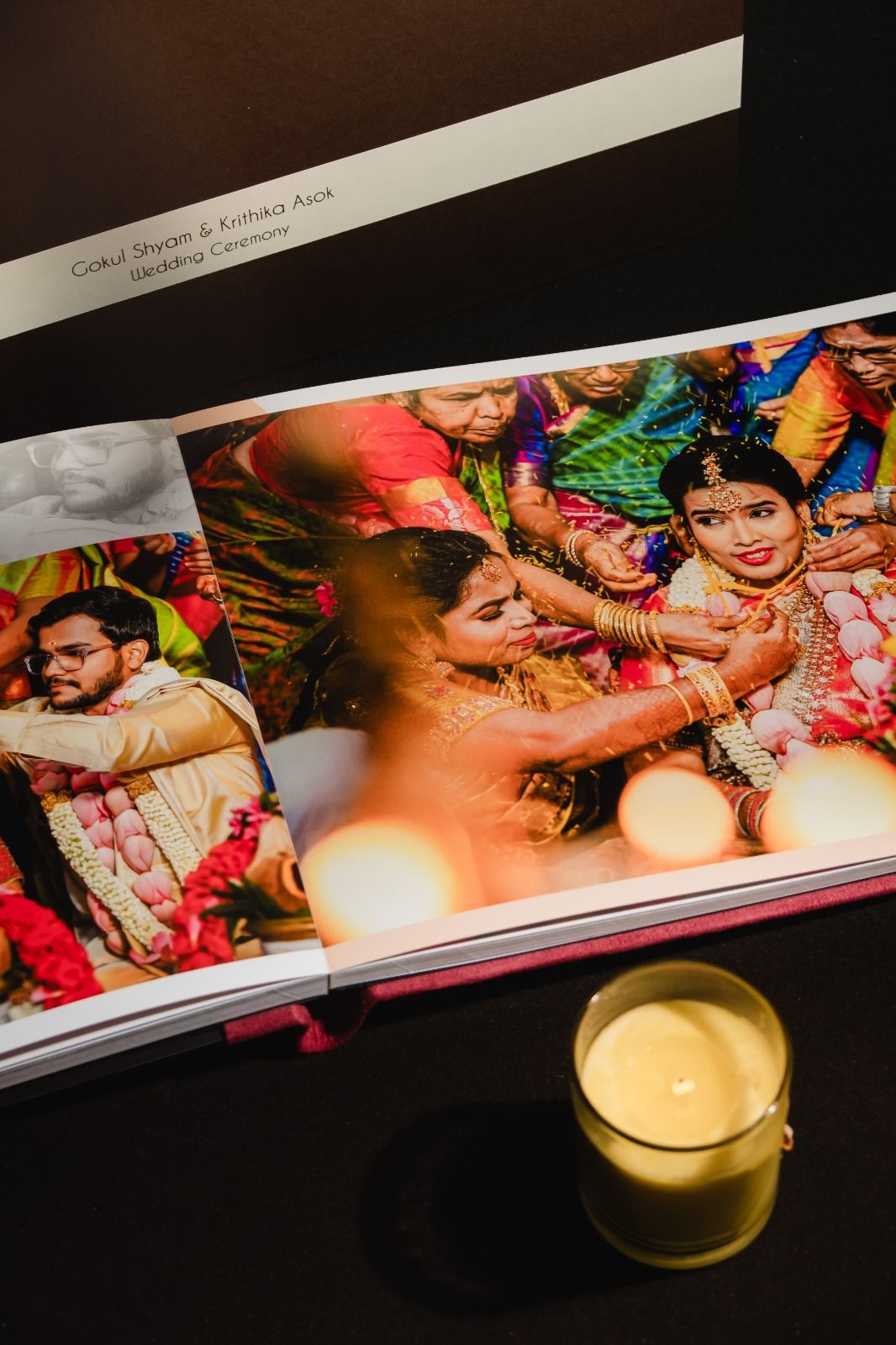 Indian wedding photo album open to colorful ceremony page with candle, showing bride in traditional jewelry and attire.
