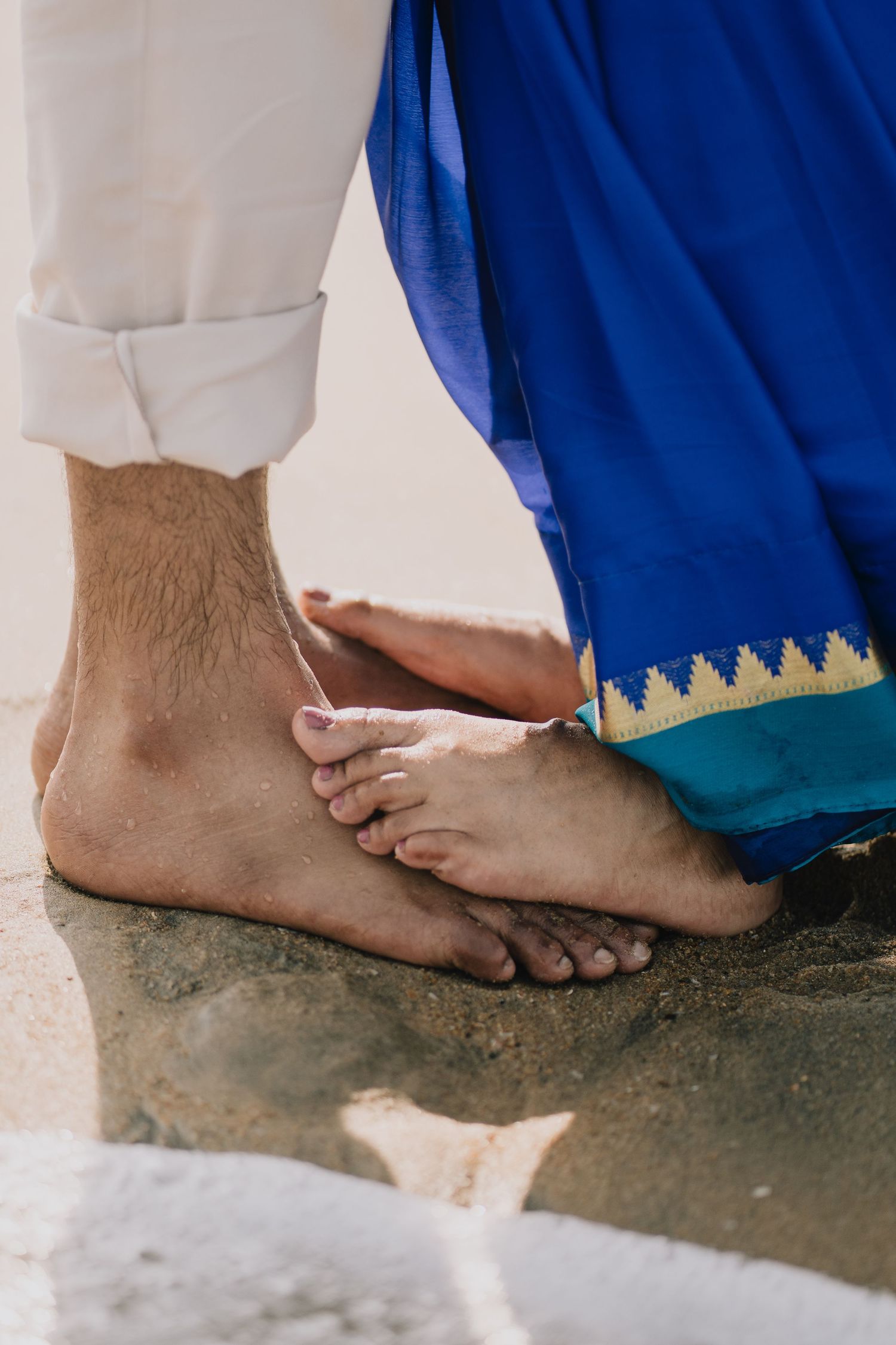 Close-up sequence of bare feet walking on a dusty concrete floor against a white and blue wall.