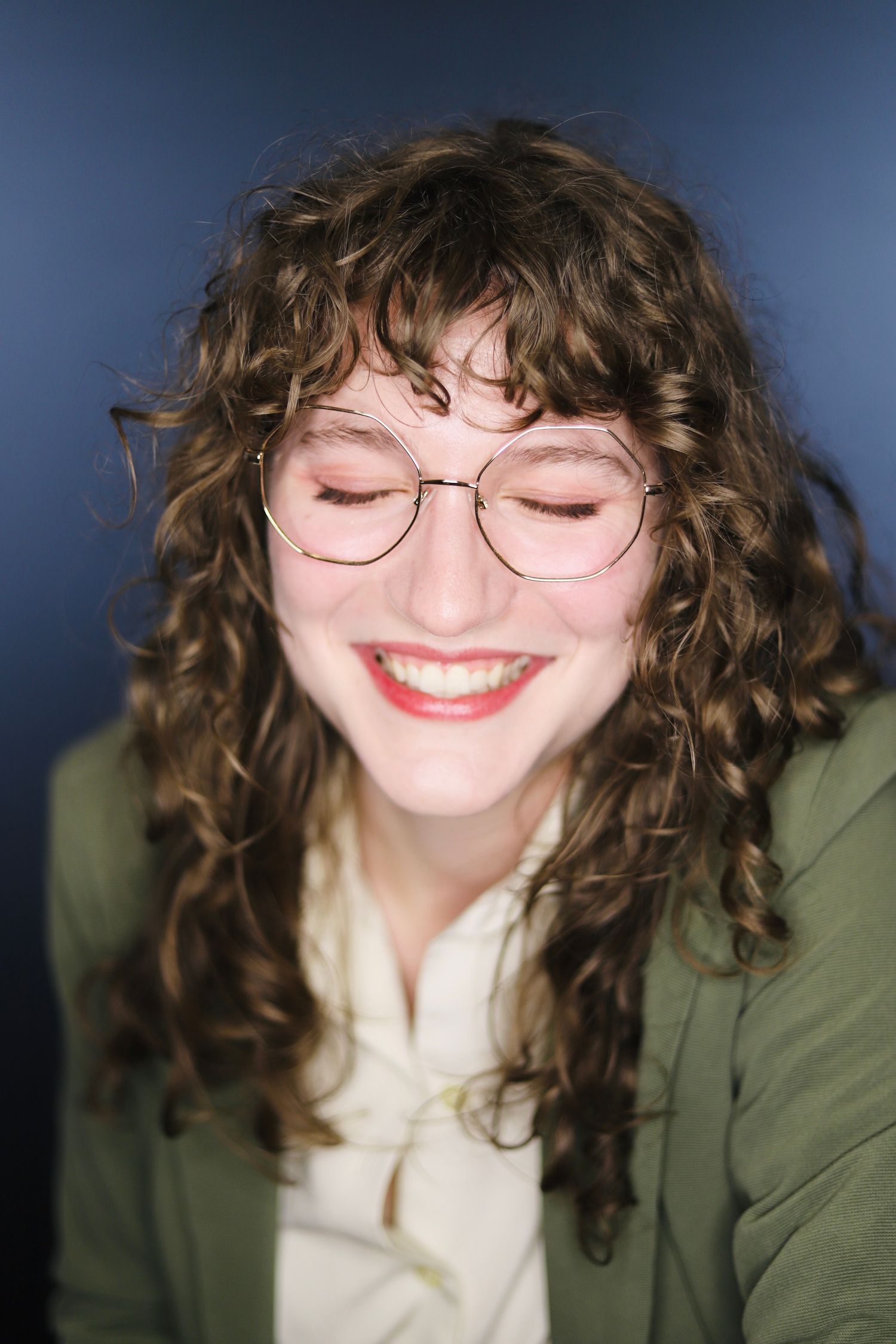 Artistic portraits showing round glasses and curly hair with a green jacket.