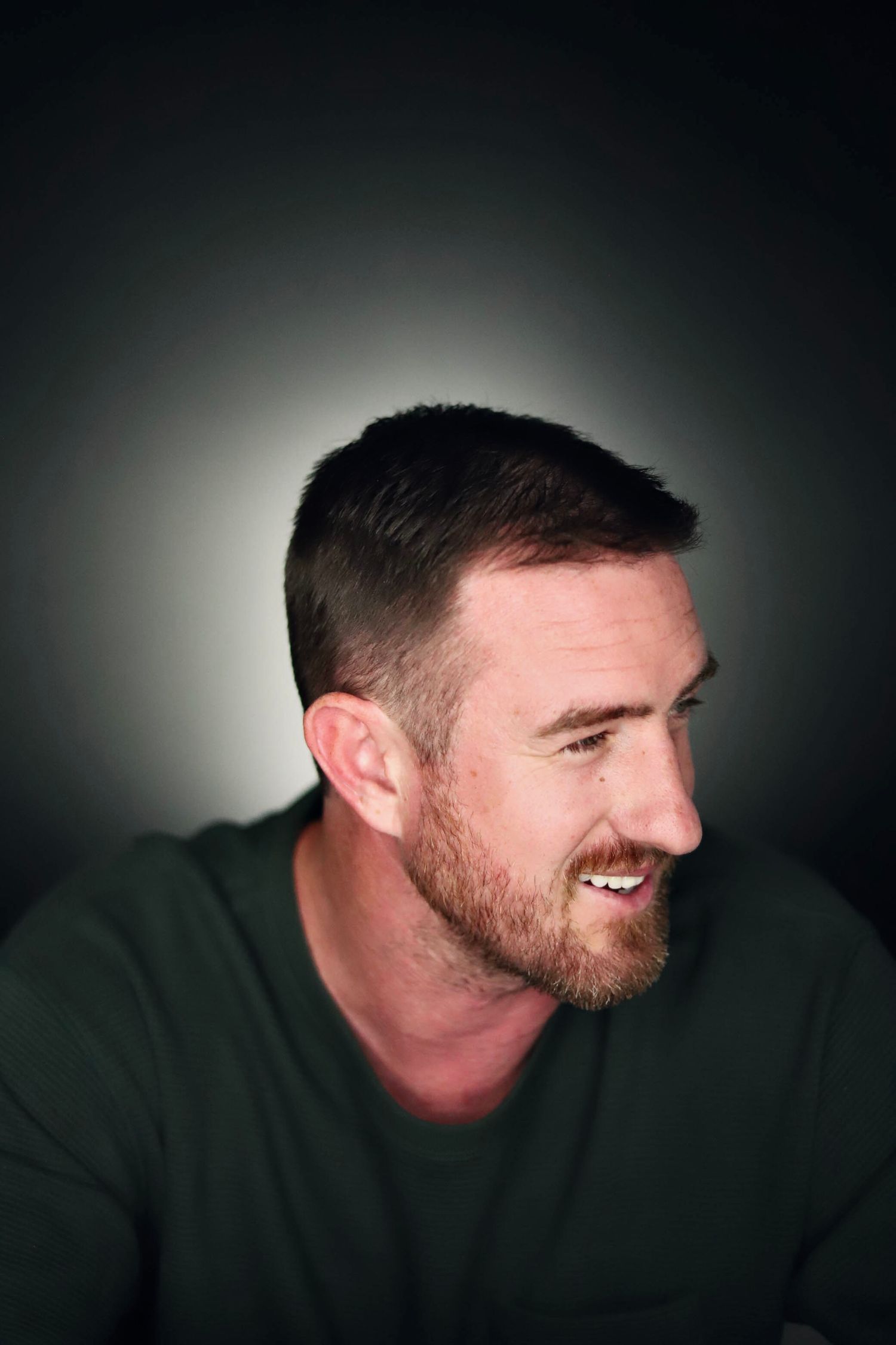 Dramatic side profile shots of a bearded person in green sweater against dark background.