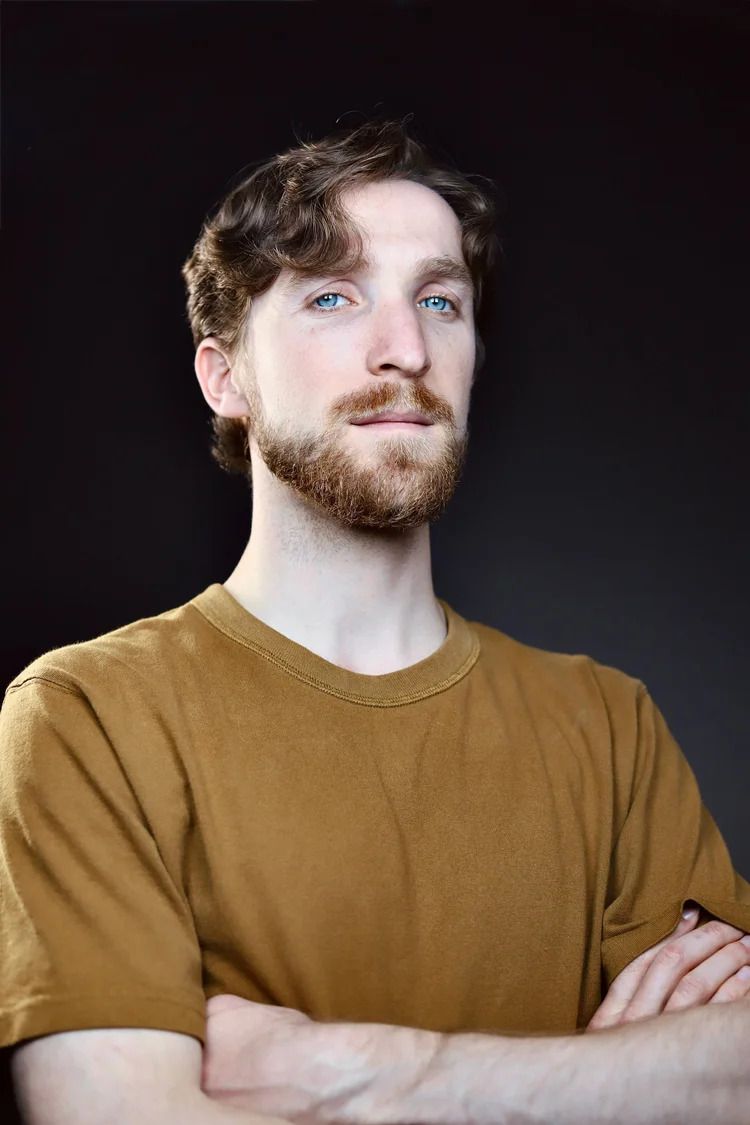 Portrait series of person in brown sweater with beard against dark background.