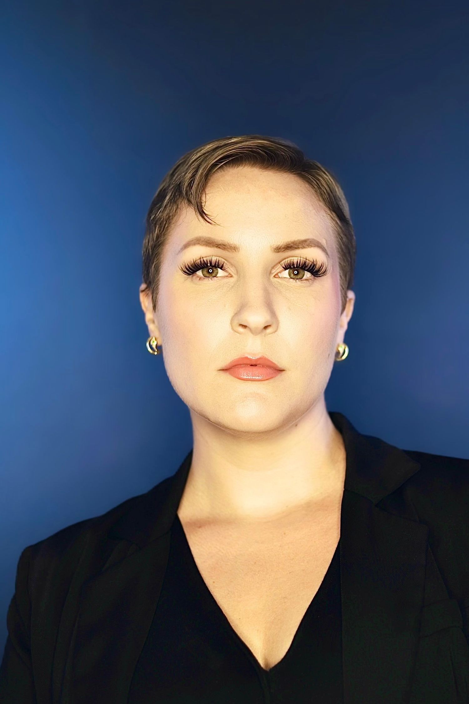 Close-up portrait with bold makeup against deep blue background.