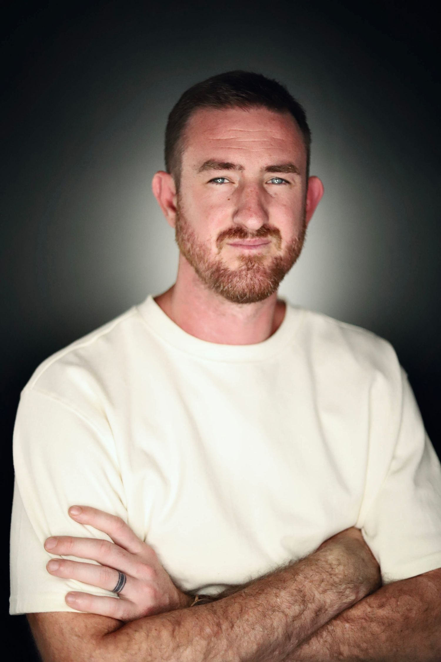 Studio portraits of person in white shirt with red beard against dramatic lighting.