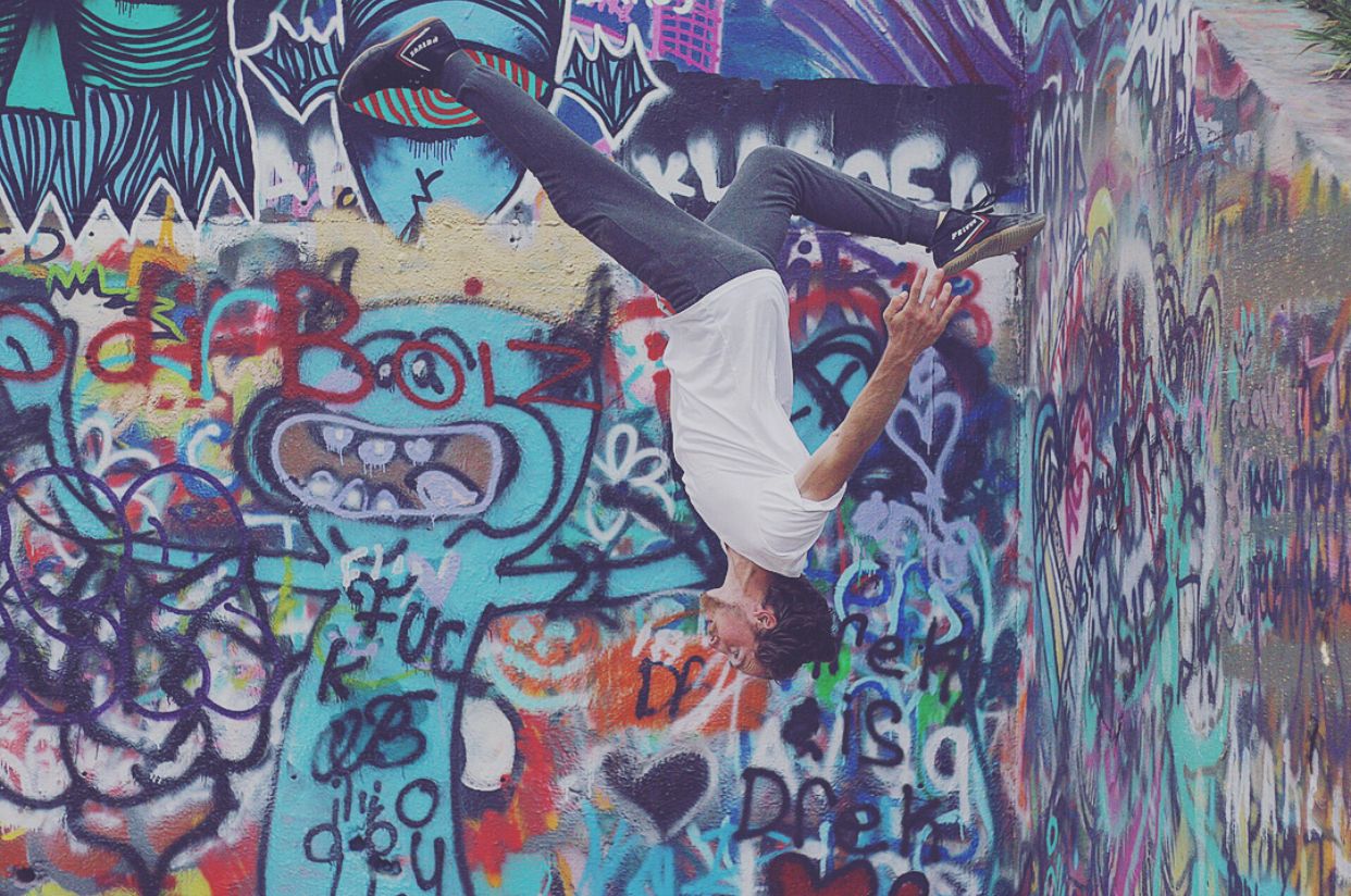 Urban wall covered in vibrant turquoise and purple graffiti artwork.