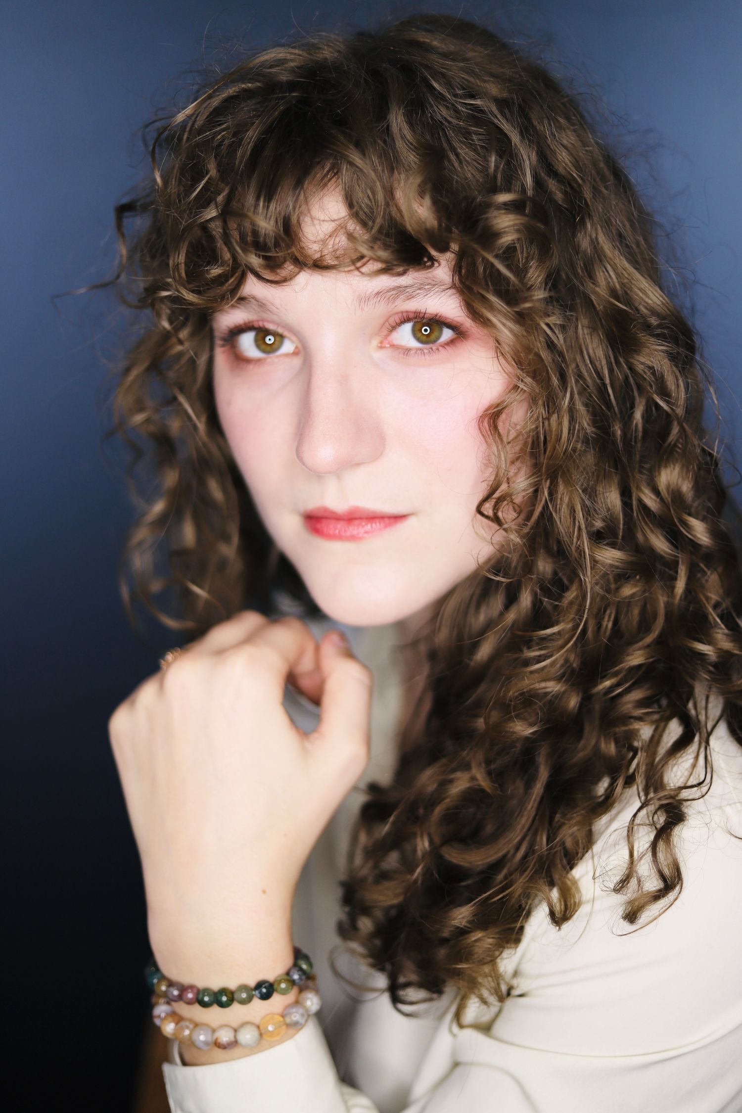 Portrait series showing playful expressions with curly brown hair against blue background.