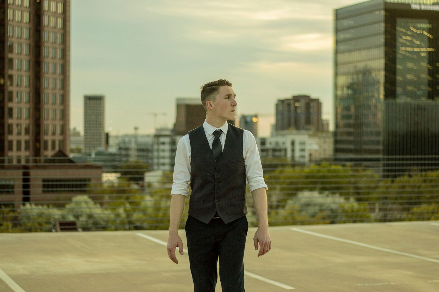 Figure in vest and dress pants standing against urban cityscape backdrop.