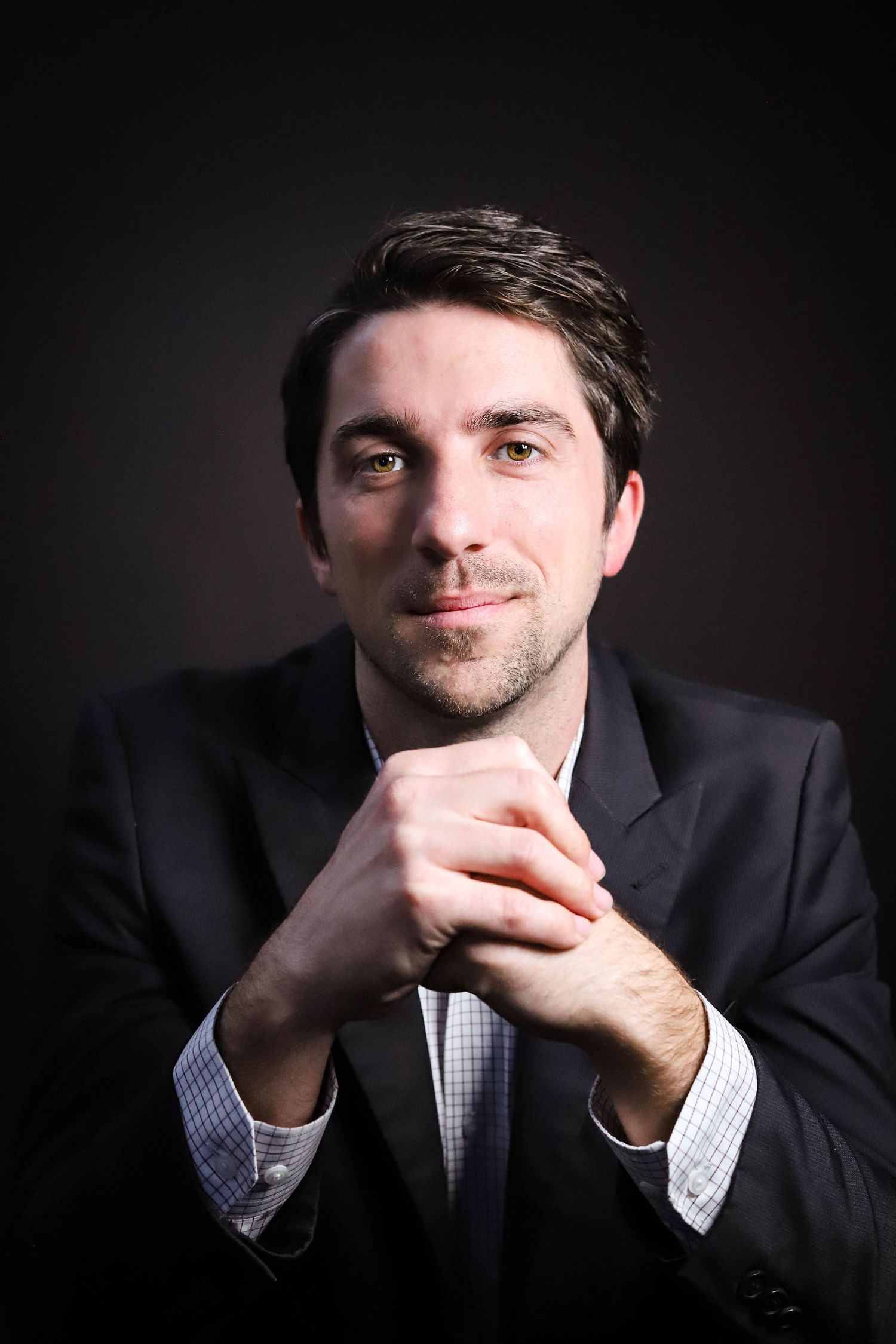 Professional portrait series showing contemplative poses in dark lighting against black background.