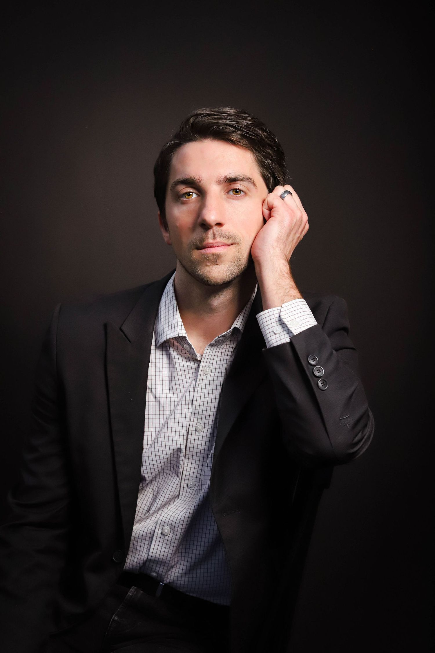 Professional studio portrait series showing contemplative poses against dark background in business attire.