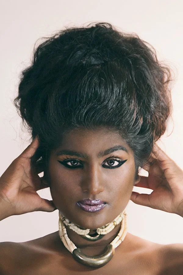 Creative portrait with gold facial jewelry and dramatic makeup.