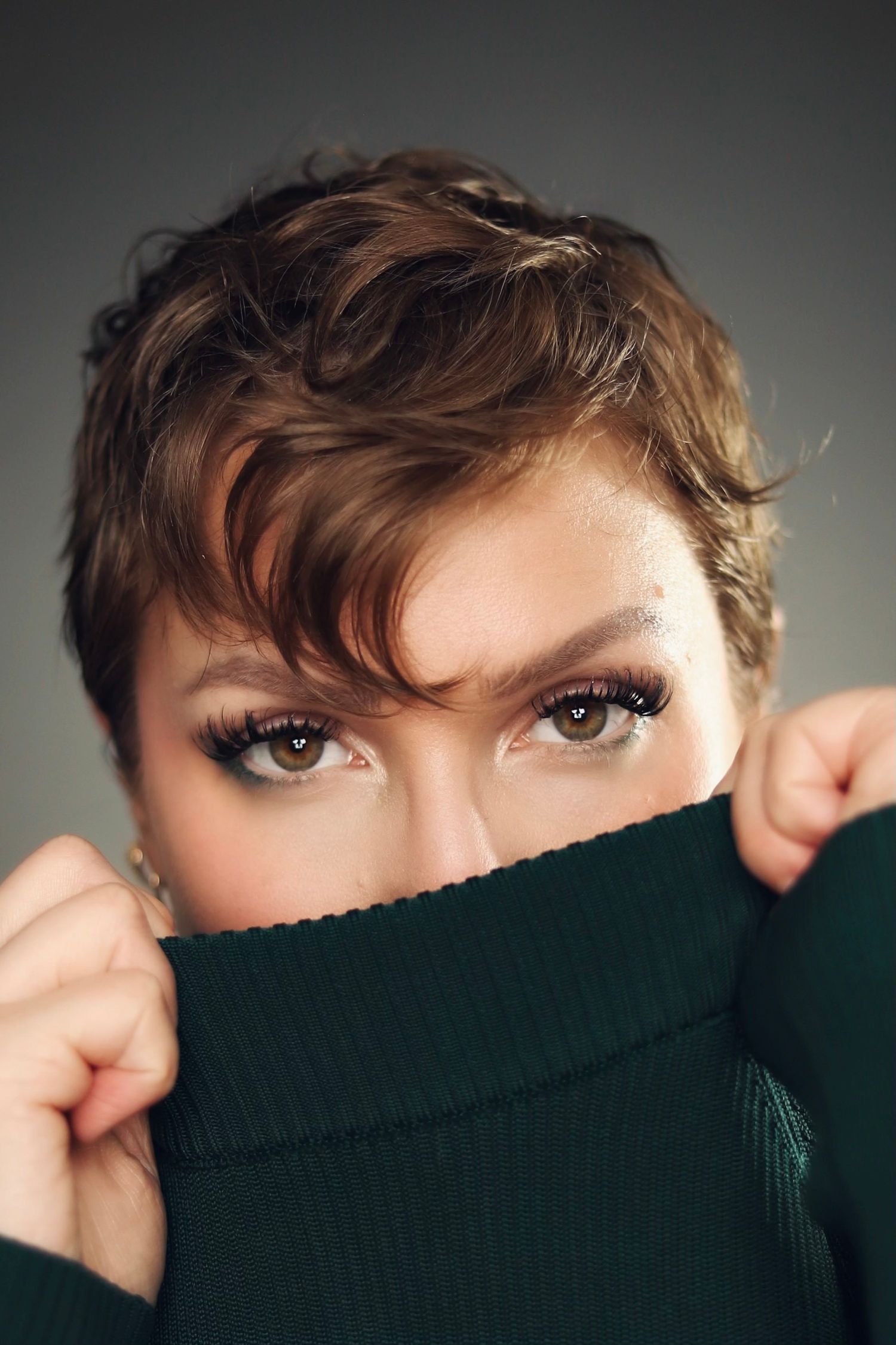 Artistic portrait with eyes peeking over black turtleneck sweater.