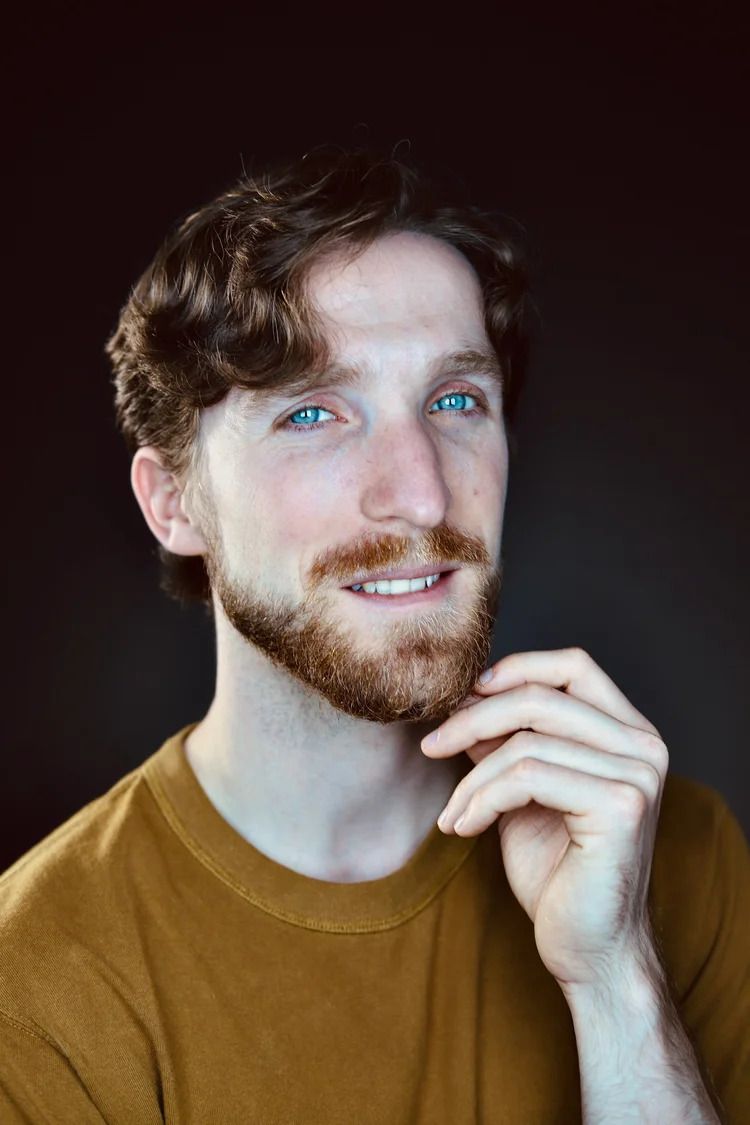 Candid expressions of person in mustard sweater with bright blue eyes.