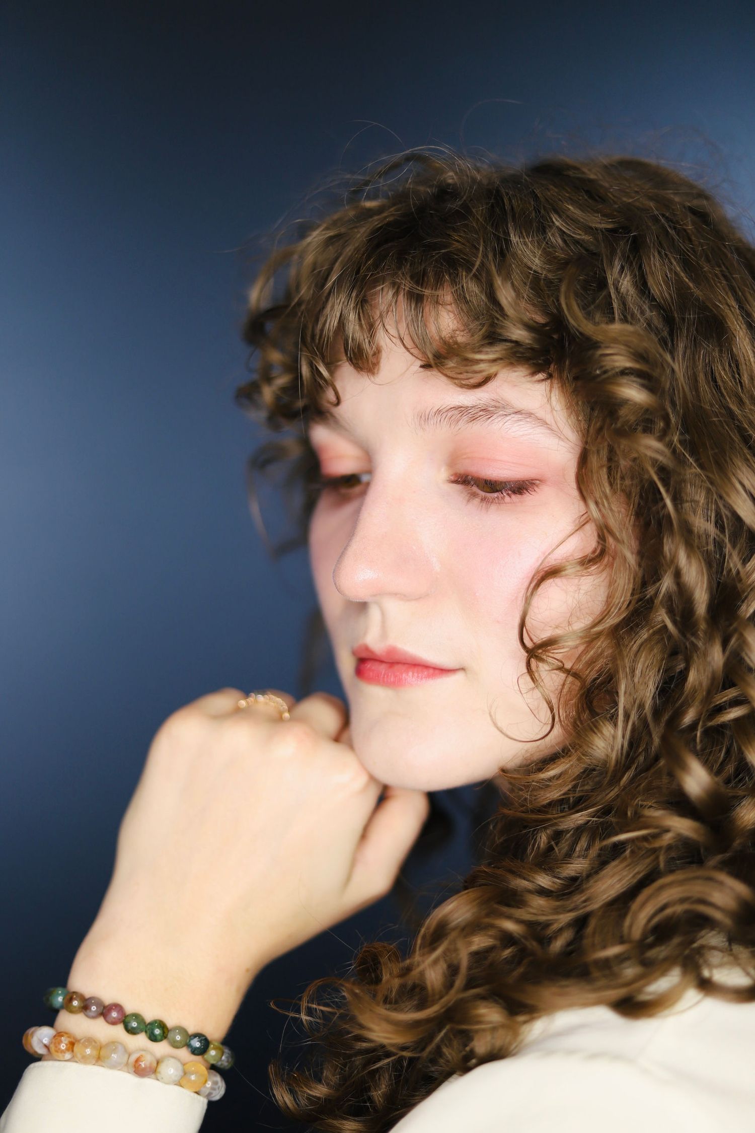 A series of profile shots showing curly brown hair and red lipstick against a dark blue background.