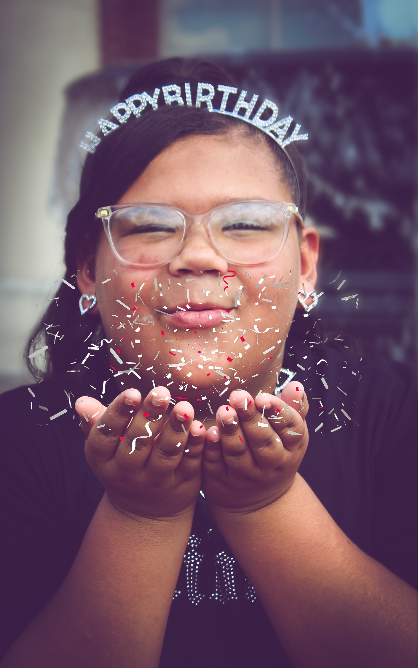 Birthday portrait of a child blowing confetti while wearing a birthday headband, capturing joy and celebration