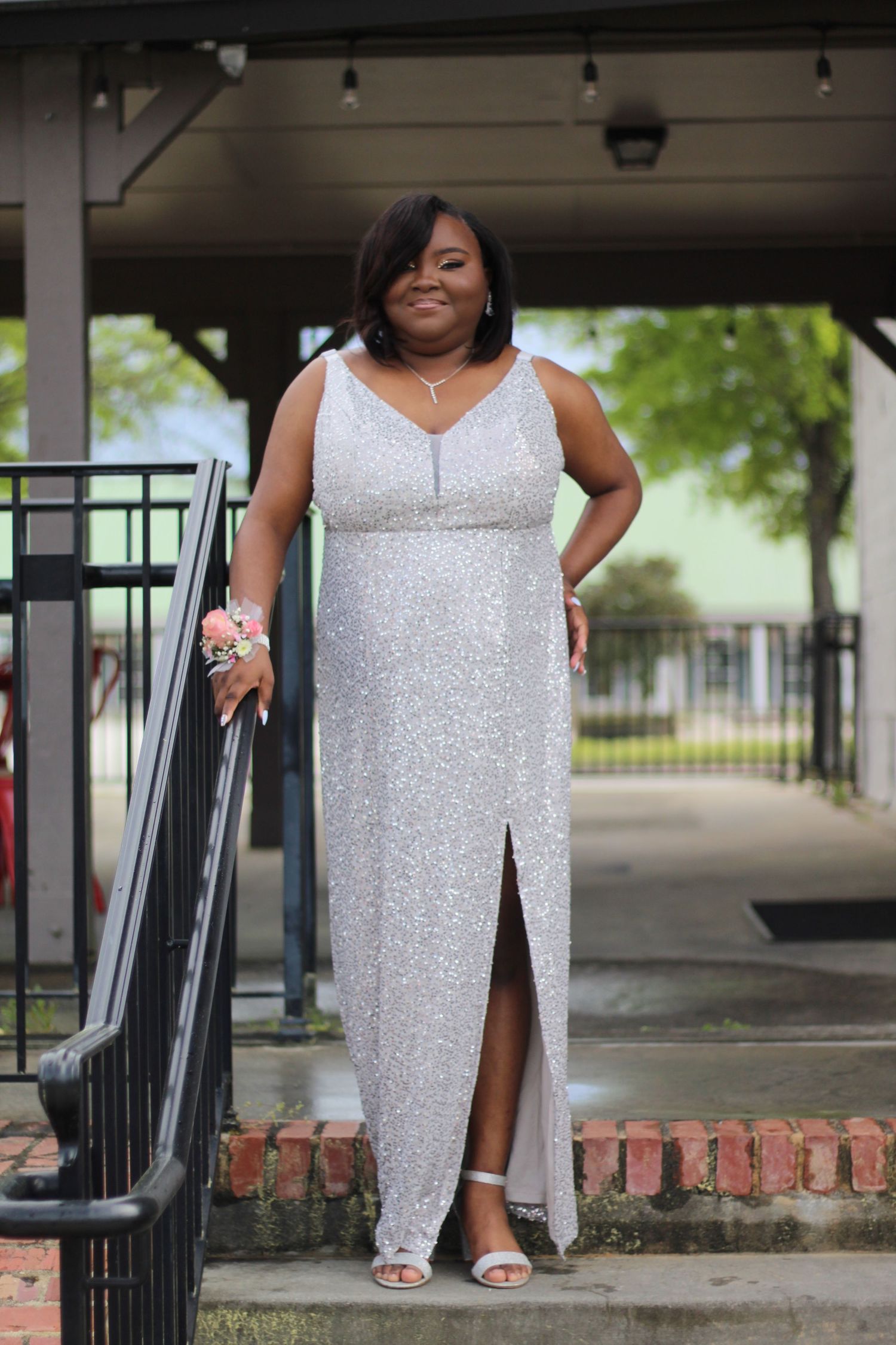 Milestone portrait of a woman in a silver gown standing confidently, celebrating a special occasion