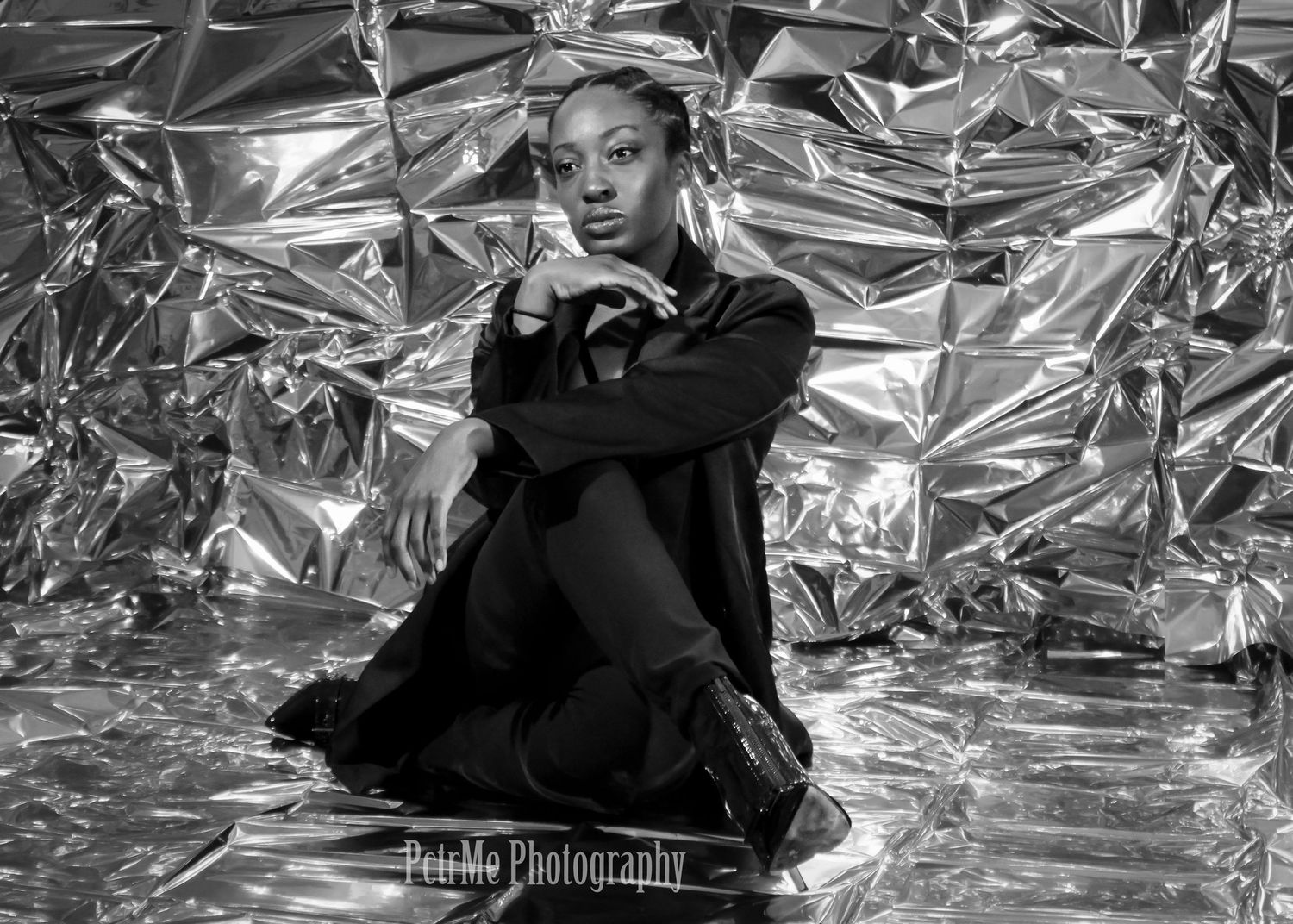 Fashion modeling portrait of a woman seated confidently against a textured studio backdrop, showcasing strength and style