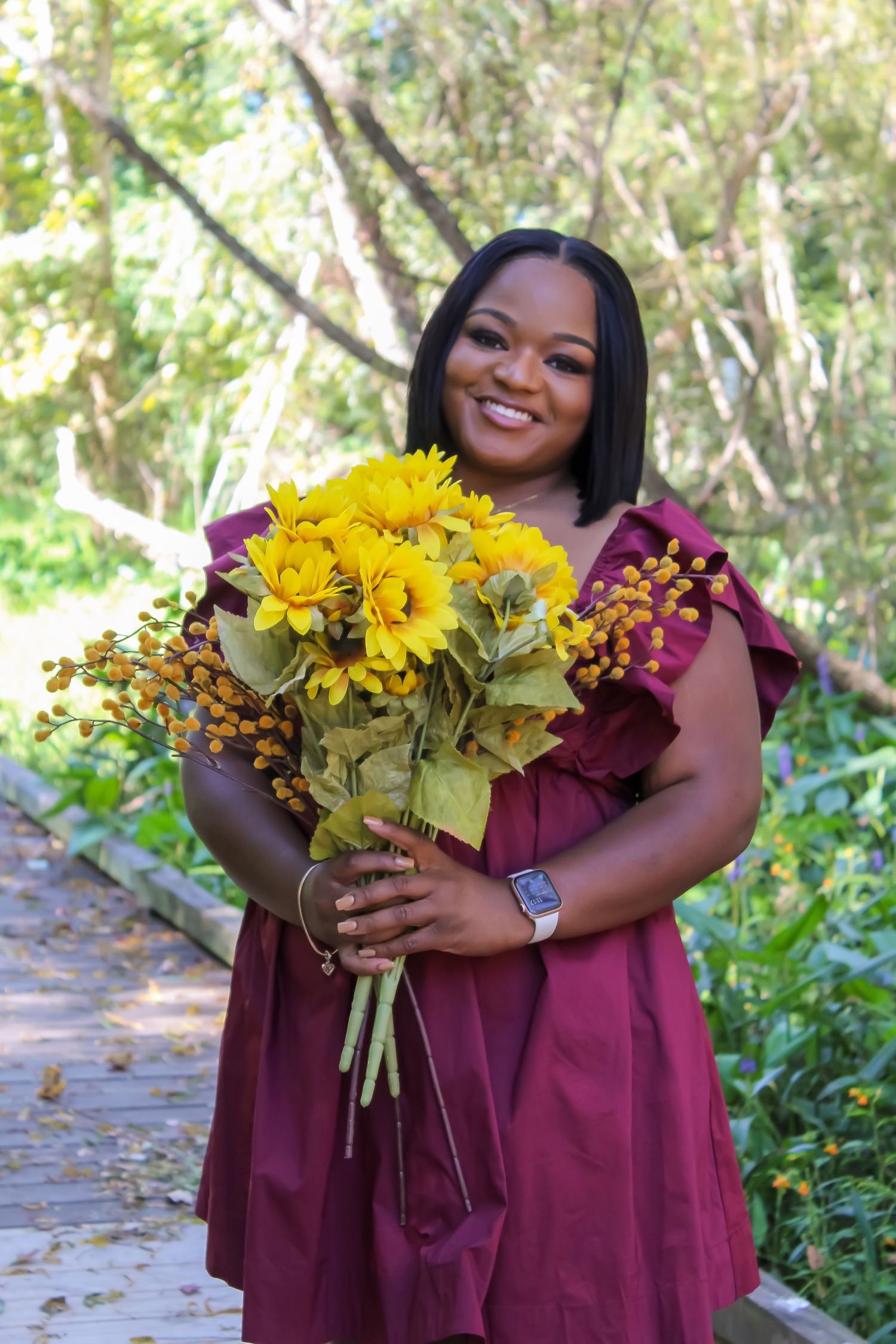 Lifestyle portrait of a woman holding sunflowers outdoors, capturing warmth, confidence, and natural beauty