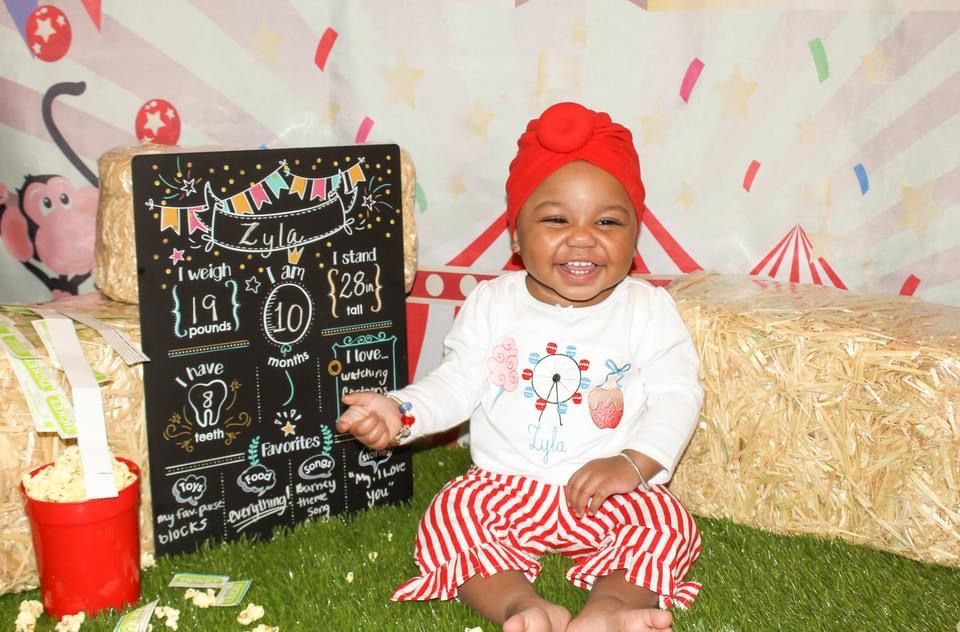 Smiling baby sitting during a playful milestone portrait session celebrating personality and joy