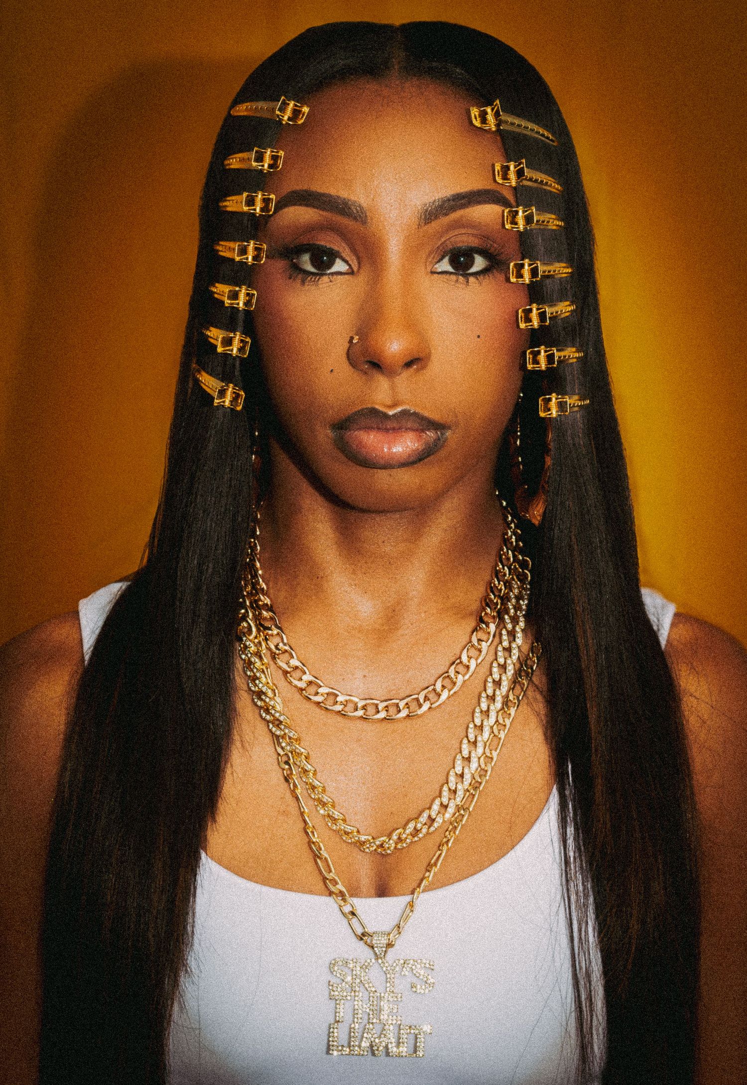 Close-up beauty shots with decorative gold hair clips and layered chain necklaces.