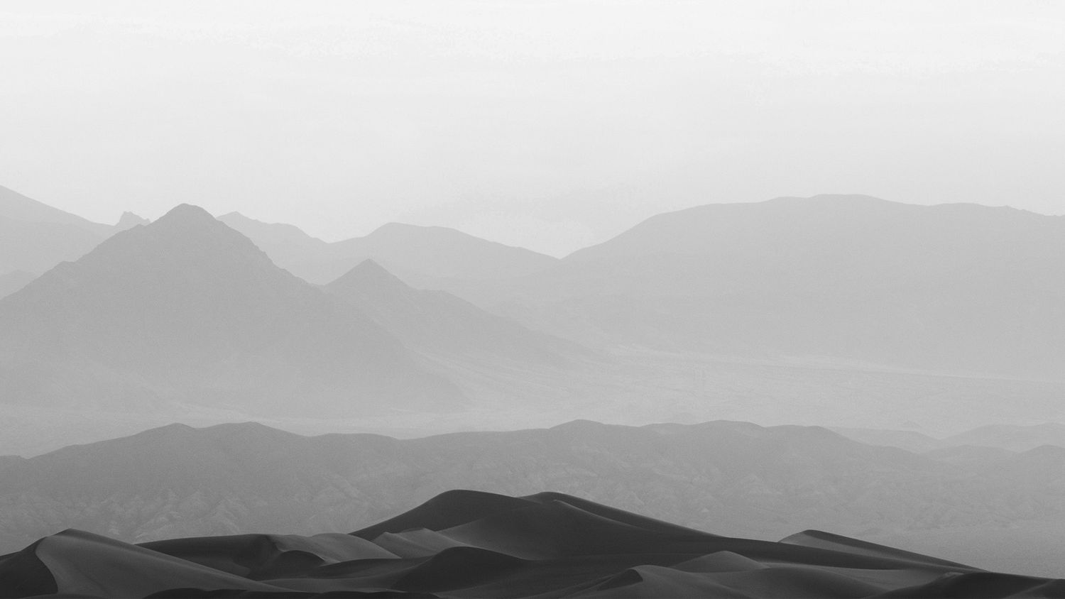 Minimalist mountain landscape with layered ridges fading into misty distance.