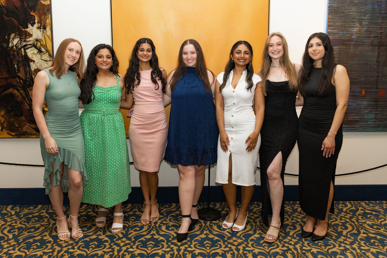 Group photo of women in formal attire standing together at an event.