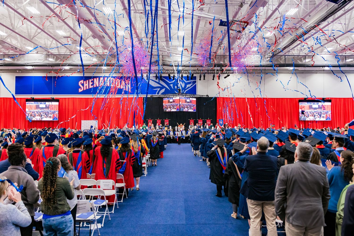 Large graduation ceremony with large crowd seated in rows at an indoor venue.