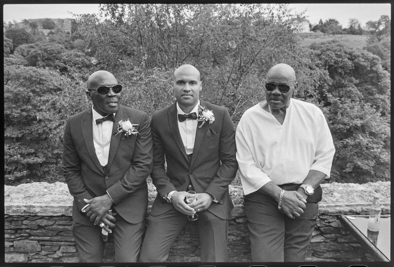 Groomsmen in formal attire posing together outdoors at a wedding.
