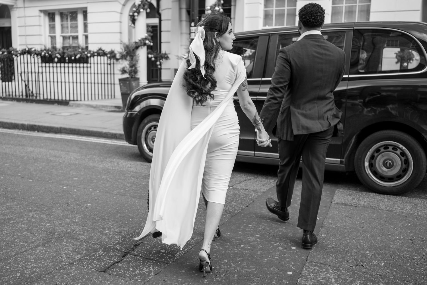 Wedding couple walking away on cobblestone street in black and white photography.