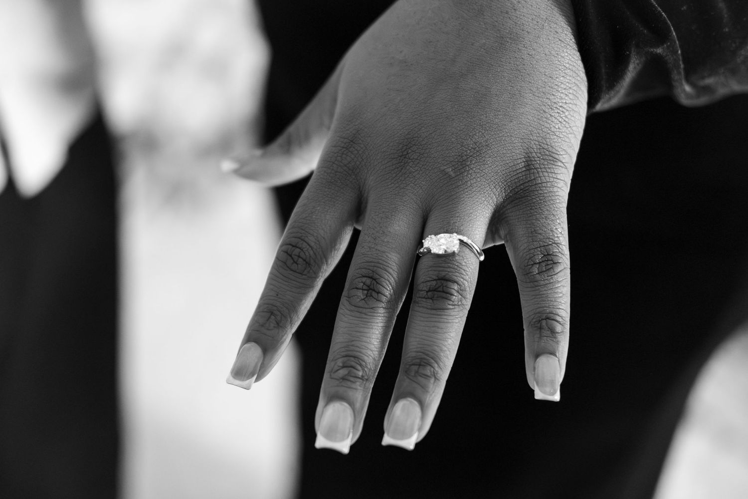 Close-up black and white photo of hands showing rings.