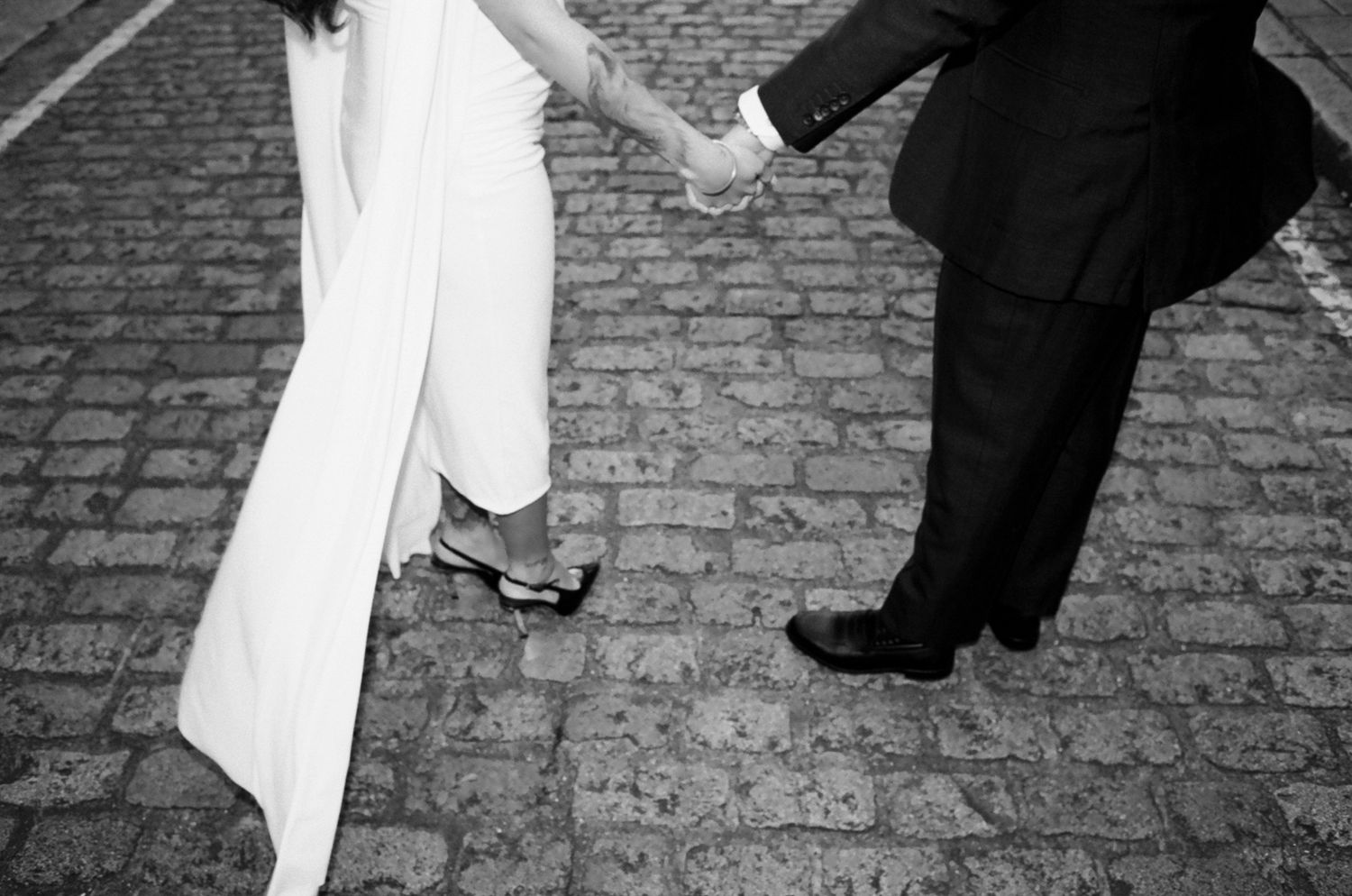 Partial view of formal outfits against brick pavement in black and white photography.
