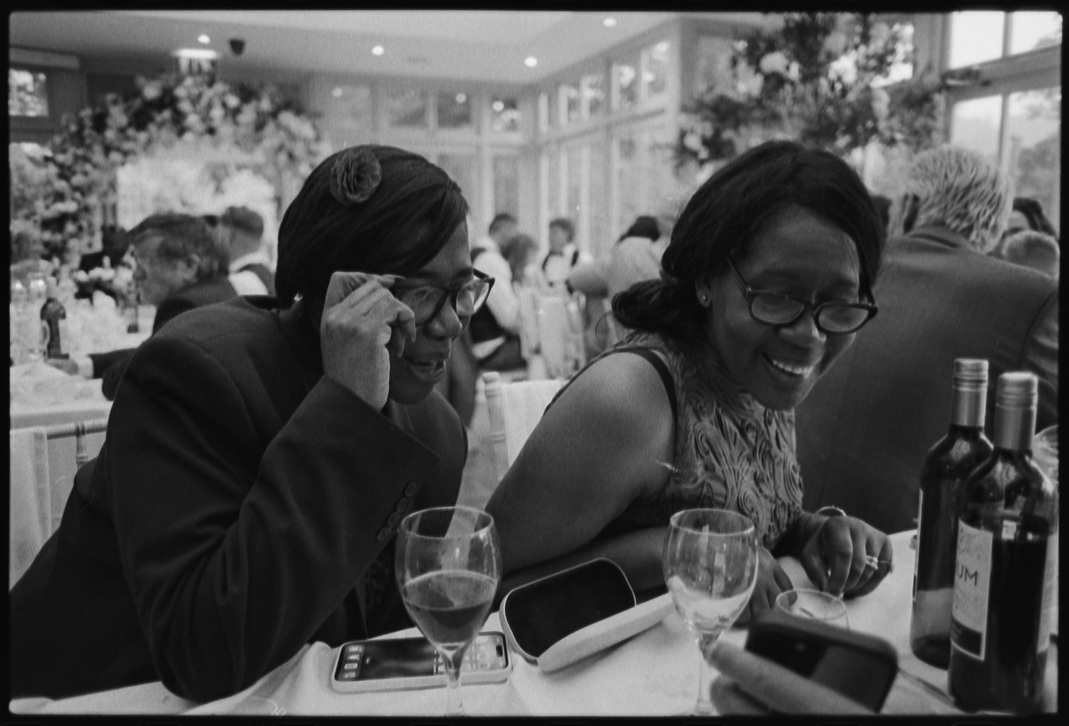 Black and white photo of wedding reception guests enjoying drinks and conversation.