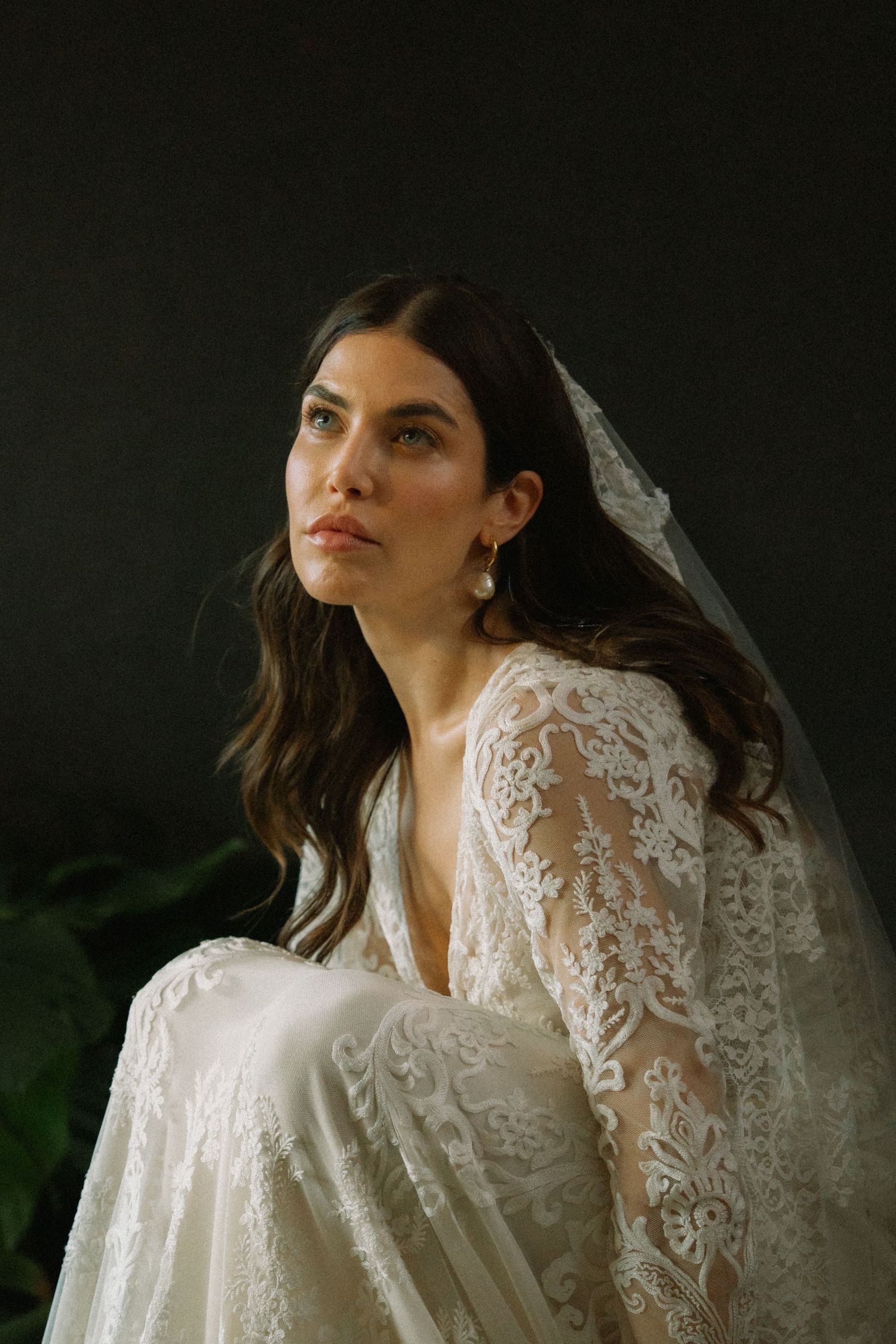 Ethereal bridal portraits featuring delicate lace wedding dress against dark background.